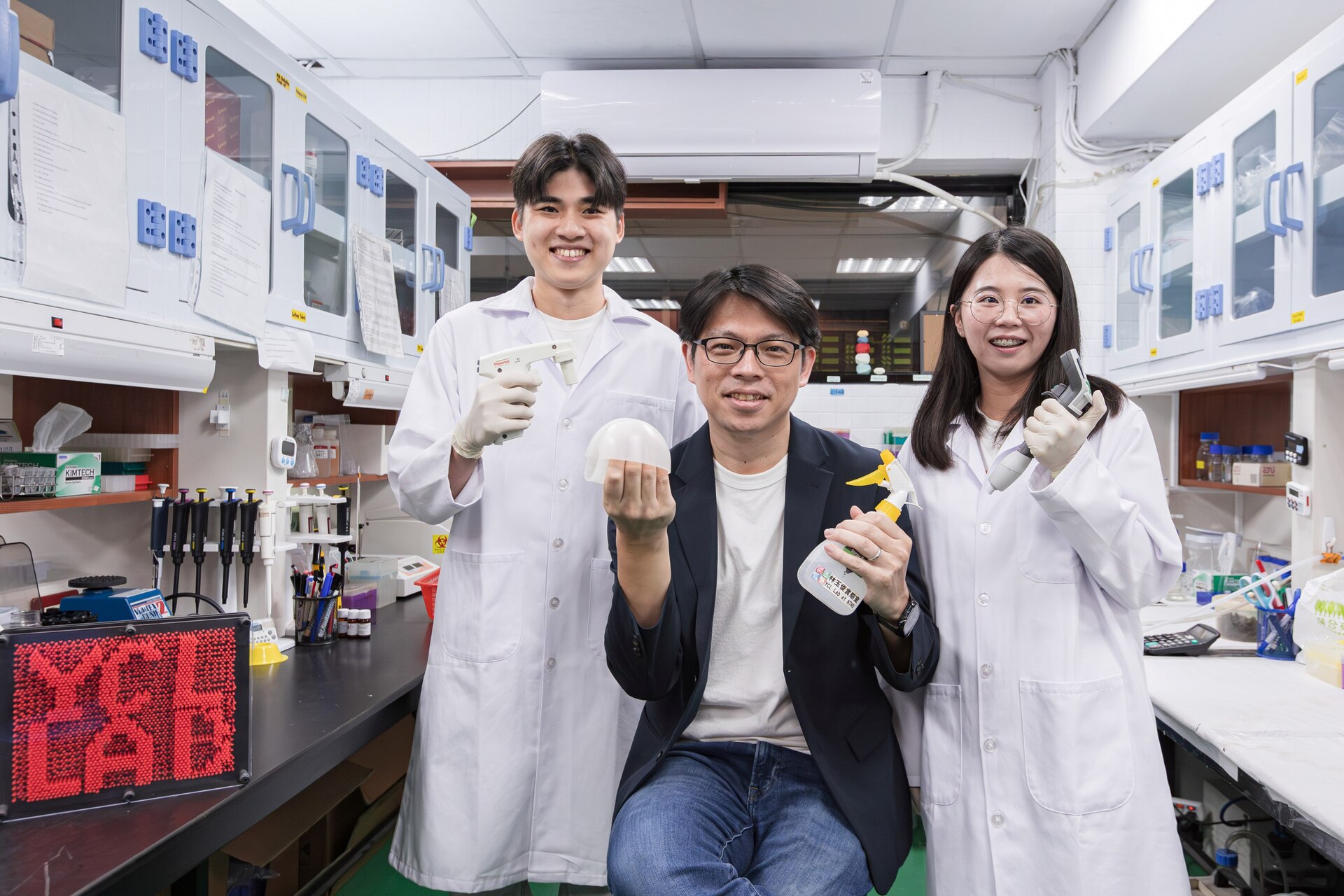 Lin (林玉俊) (center) of NTHU's Institute of Molecular Medicine led a research team consisting of research assistant Shiau-Chi Chen (陳筱奇) (right) and master's student Neng-Jie Zeng (曾能杰) (left) to develop the