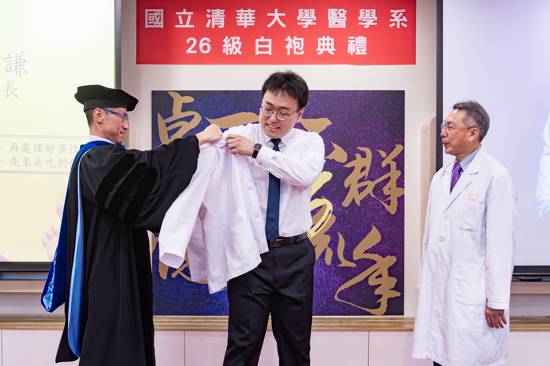 President W. John Kao (高為元) (left) adorned Ho-Chien Shen (沈和謙), a member of the first class of medical students at NTHU, with a white coat.